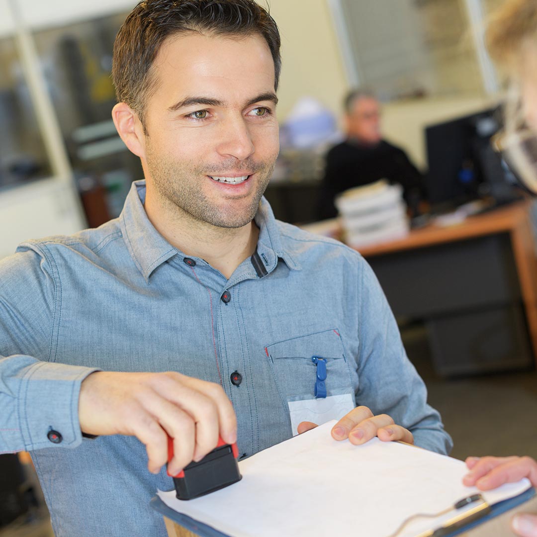 smiling man using a stamp on a document